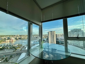 Ein Zimmer mit großem Fenster und Blick auf eine Stadtlandschaft, einschließlich eines Flusses und Wolkenkratzern.