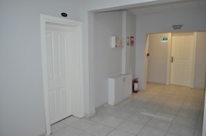 Un couloir avec des portes blanches, un extincteur et un panneau indiquant un espace réservé aux fumeurs.