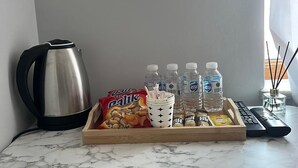 A marble countertop with a tray containing snacks, water bottles, a coffee pot, and a remote control. - Bulut Gaye Pansiyon  (Edirne)