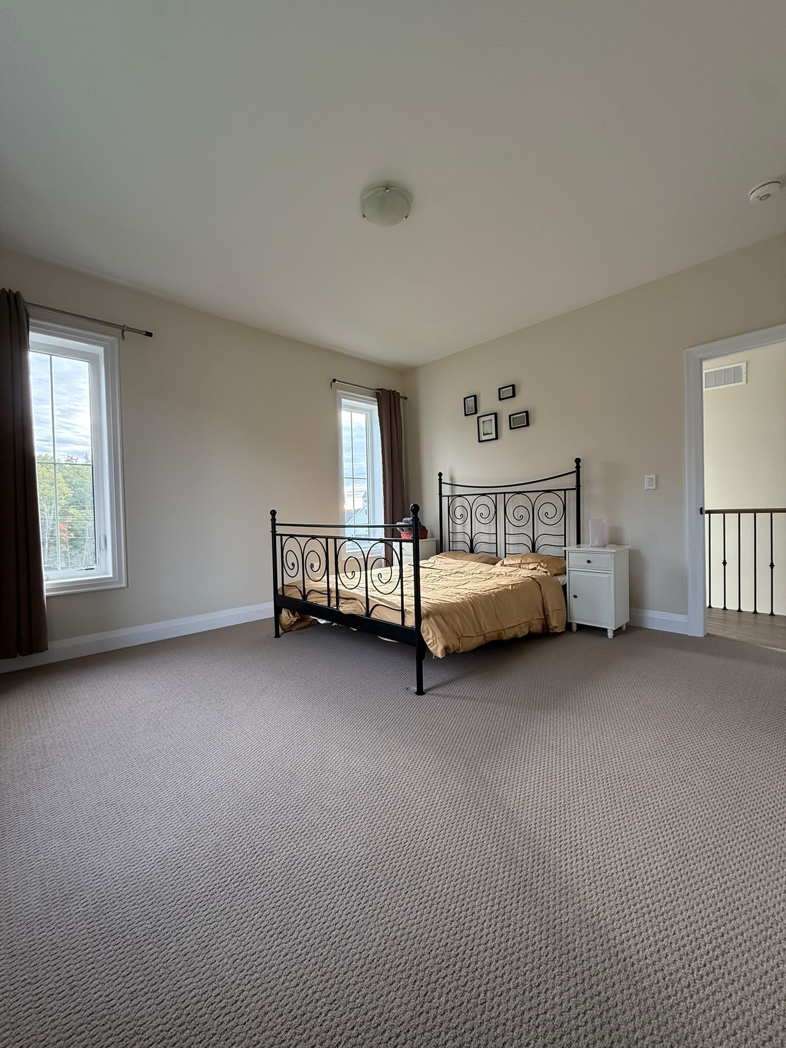 A bedroom with a single bed, a nightstand, a window with curtains, and a door.
