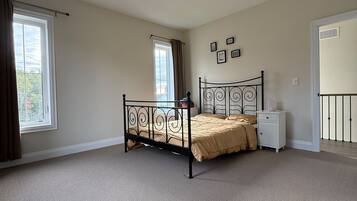 A bedroom with a single bed, a nightstand, a window with curtains, and a door.