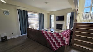 Una sala de estar con sofá, chimenea, televisor y escalera.
