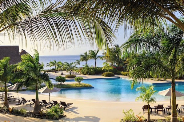 A resort pool with lounge chairs and palm trees. - Intercontinental Dominica Cabrits Resort & Spa, an IHG Hotel (Portsmouth)
