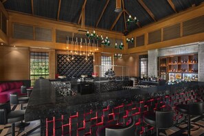 A bar area with a black bar counter, red accents, and a variety of bottles. - Intercontinental Dominica Cabrits Resort & Spa, an IHG Hotel (Portsmouth)
