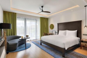 Una habitación de hotel moderna con una cama grande, un escritorio, una silla y un ventilador de techo.