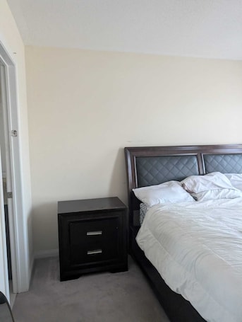 A bedroom with a bed, a nightstand, and a door.. Affordable GTA stay during FIFA 2026
