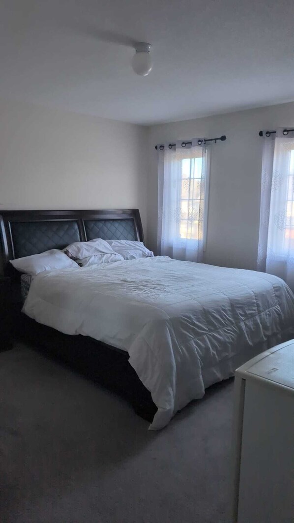 A bedroom with a bed, a nightstand, a dresser, and a ceiling light.