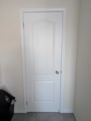 A white door with a silver doorknob, a small rectangular panel, and a baseboard.