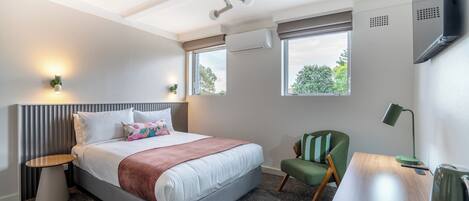 Ein Hotelzimmer mit Bett, Schreibtisch, Stuhl, Fernseher und Fenster.