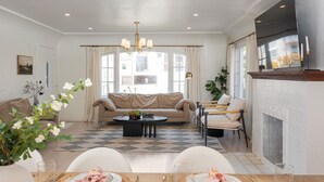 Una sala de estar moderna con sofá, mesa de centro, mesa de comedor para dos personas y chimenea.
