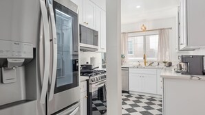 Una cocina moderna con refrigerador, horno, microondas y piso a cuadros.