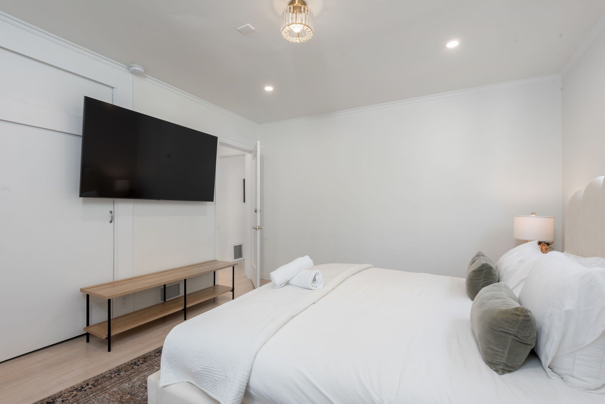 A bedroom with a bed, a bench, a TV, and a lamp.