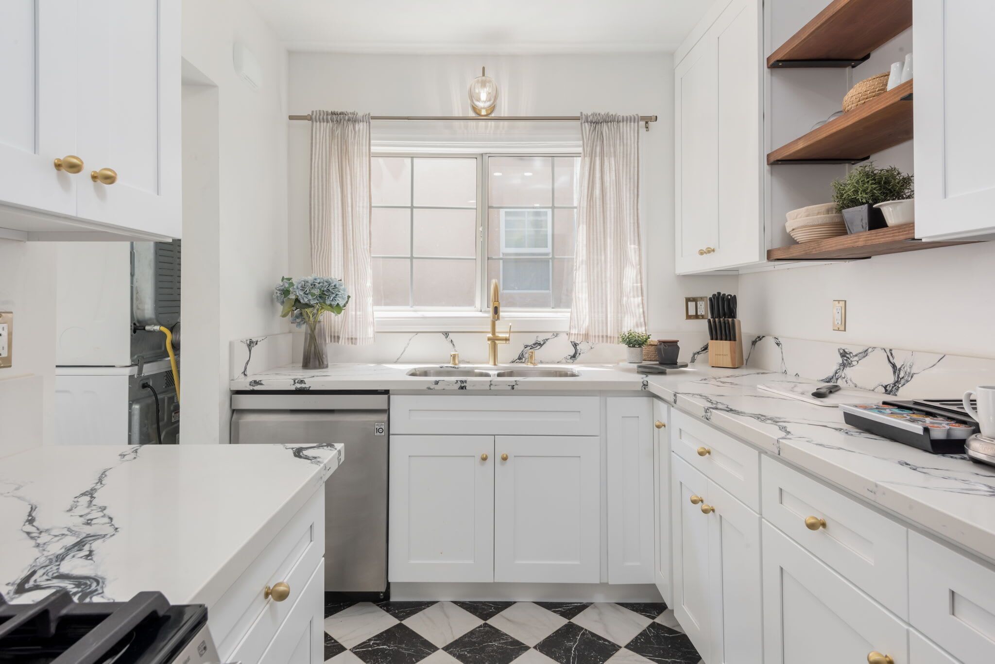 A modern kitchen with white cabinetry, a double sink, and a marble countertop.