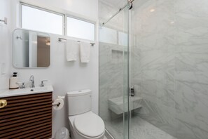 Un bagno moderno con cabina doccia in vetro, mobile bagno in legno e servizi igienici.
