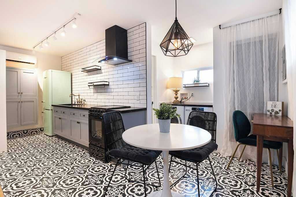 Una cocina moderna con estufa negra, armarios blancos y piso estampado.