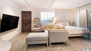 Een moderne slaapkamer met een bed, een televisie, een houten deur en een raam.