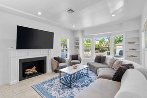 Una sala de estar con chimenea, sofás, una mesa de centro y un televisor.