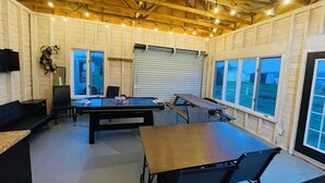 Un grand espace intérieur comprenant une table de ping-pong, des sièges et de grandes fenêtres.