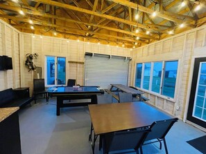 A spacious indoor area with a ping pong table, seating, and large windows.