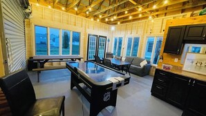 Un grand espace intérieur comprenant une table de billard, des sièges et un coin cuisine.