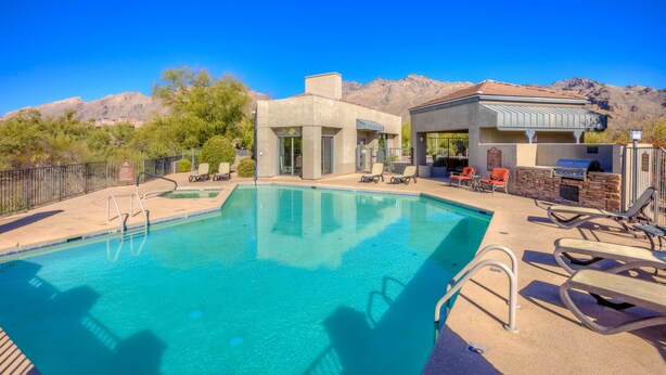A swimming pool with lounge chairs, a barbecue area, and a mountain backdrop. - Luz de Ventana | Redesigned 2BR Condo · Pools + Fitness · Mountain Views (Tucson)