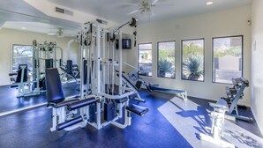 A gym with ceiling fans, exercise equipment, and large windows. - Luz de Ventana | Redesigned 2BR Condo · Pools + Fitness · Mountain Views (Tucson)