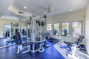 Ein Fitnessstudio mit Deckenventilatoren, Trainingsgeräten und großen Fenstern.