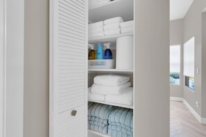 Ein ordentlich eingerichteter Kleiderschrank mit Regalen voller gefalteter Handtücher, einem Tablett für Toilettensektakel und einem Fenster mit Blick.