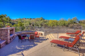 An outdoor patio with lounge chairs, a fire pit, and a view of a hilly landscape. - Luz de Ventana | Redesigned 2BR Condo · Pools + Fitness · Mountain Views (Tucson)