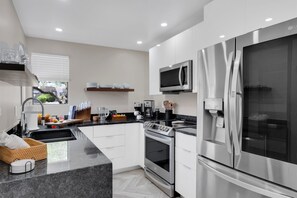 Una cocina moderna con horno empotrado, microondas y refrigerador de acero inoxidable.