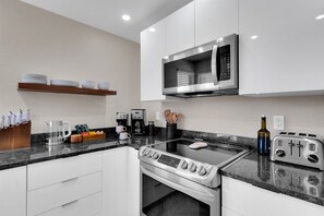 Eine moderne Küche mit weißen Schränken, einem Edelstahlherd, einer Mikrowelle und einem Toaster.