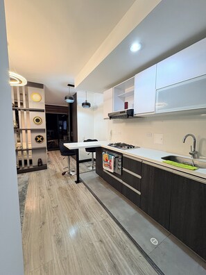 Una cocina moderna con una isla central, iluminación colgante y estufa integrada.