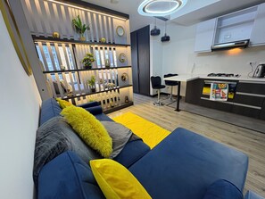 Un espacio moderno para relajarse con sofá, una cocina equipada con estufa a gas y un comedor con dos sillas.