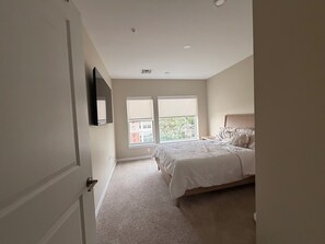 Ein Schlafzimmer mit einem Bett, einem Fenster, einer Tür und einem Deckenlüfter.