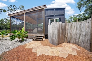 A modern house with a glass-enclosed porch, a wooden fence, and a stone pathway.