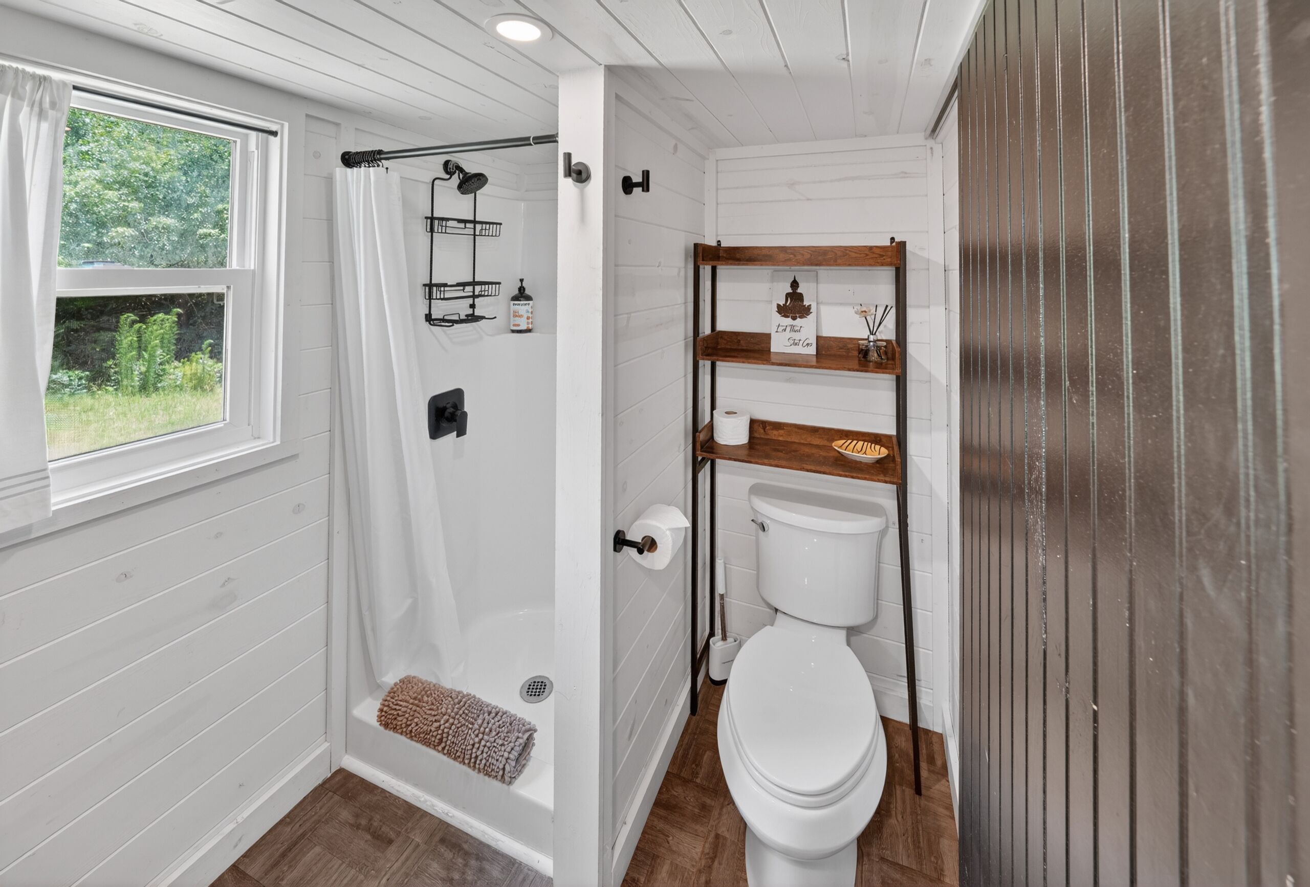Ein Badezimmer mit Dusche, Toilette und Ablagen für Toilettenartikel.