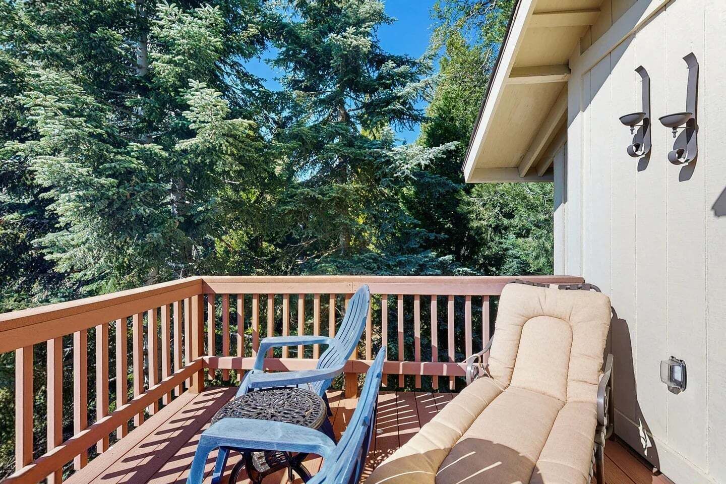 A deck with a sofa and two chairs, surrounded by trees.