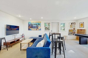A modern living room with a sectional sofa, a flat-screen TV, a pool table, and a bookshelf. - Pinetree Palace | Mountain Retreat | Games | Treetop Views | Sleeps 6 (Lake Arrowhead)