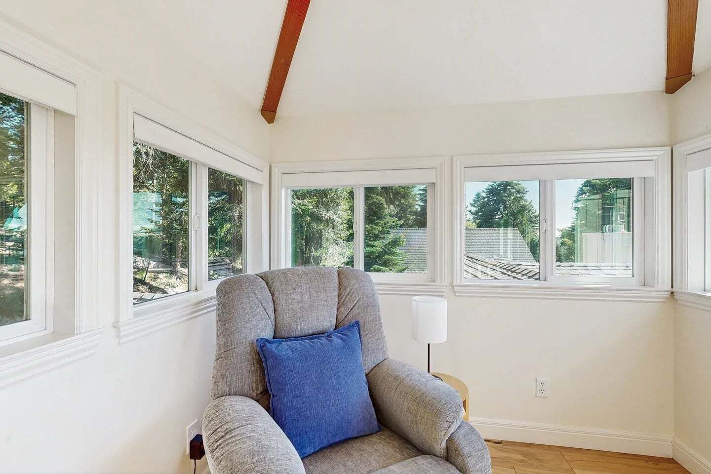 Ein Zimmer mit großem Fenster, einem Sessel und einer Lampe.