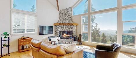 A spacious living room with a stone fireplace, large windows, and a leather sofa.