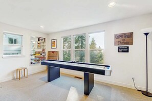 A room with a pool table, large windows, a bookshelf, and a sign indicating a nearby subway station. - Pinetree Palace | Mountain Retreat | Games | Treetop Views | Sleeps 6 (Lake Arrowhead)