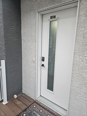 A white door with a number plate, a glass panel, and a doorknob.