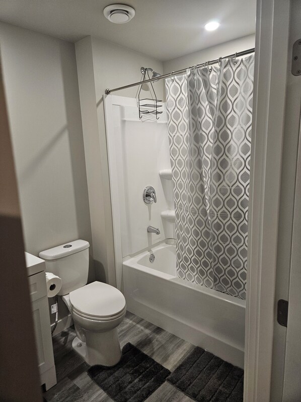 A bathroom with a toilet, a bathtub, and a shower curtain.
