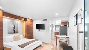 Een moderne hotelkamer met een bed, een bureau, een stoel en een televisie.