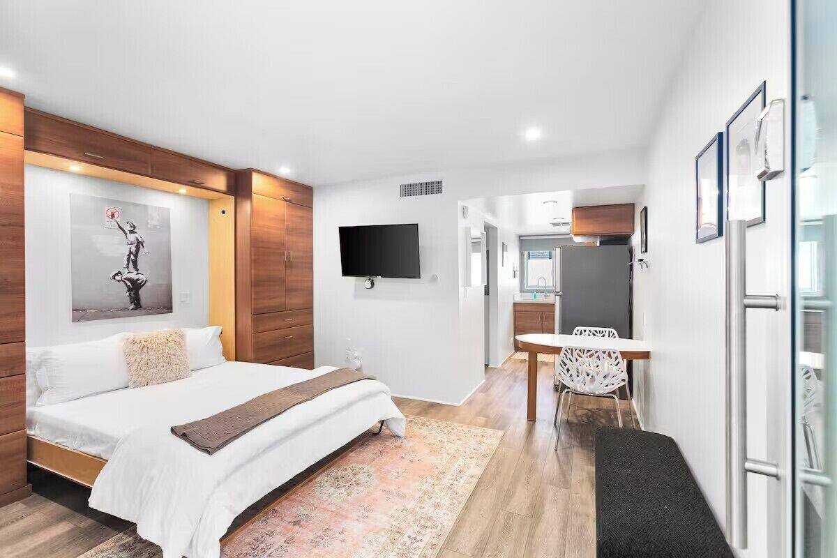 A modern hotel room with a bed, a desk, a chair, and a TV.