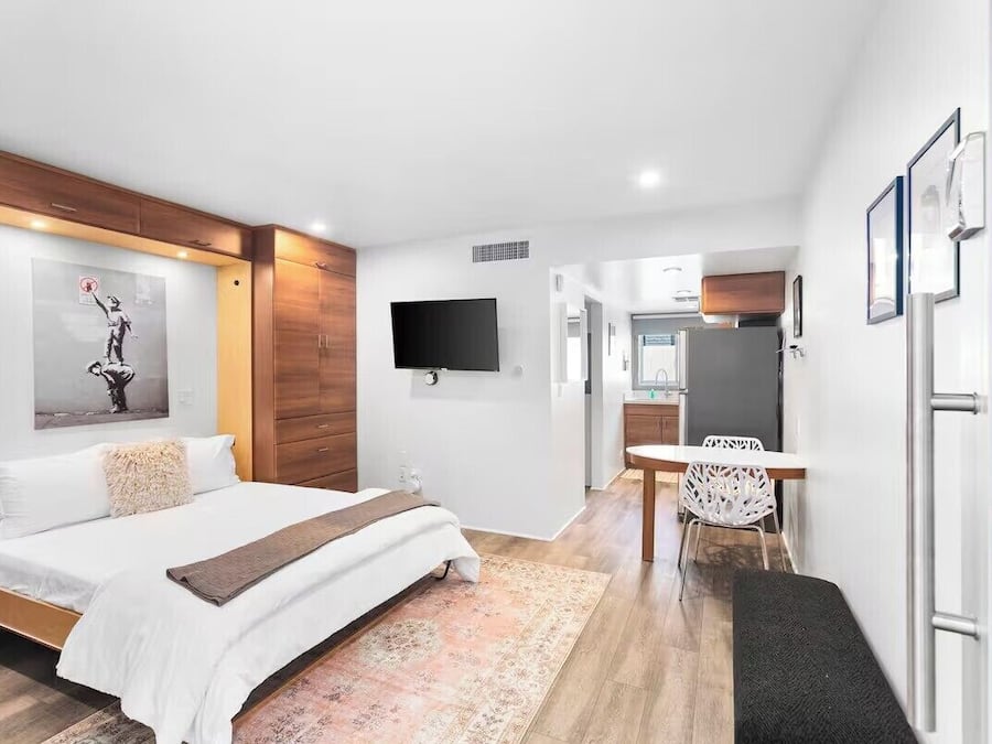A modern hotel room with a bed, a desk, a chair, and a TV.