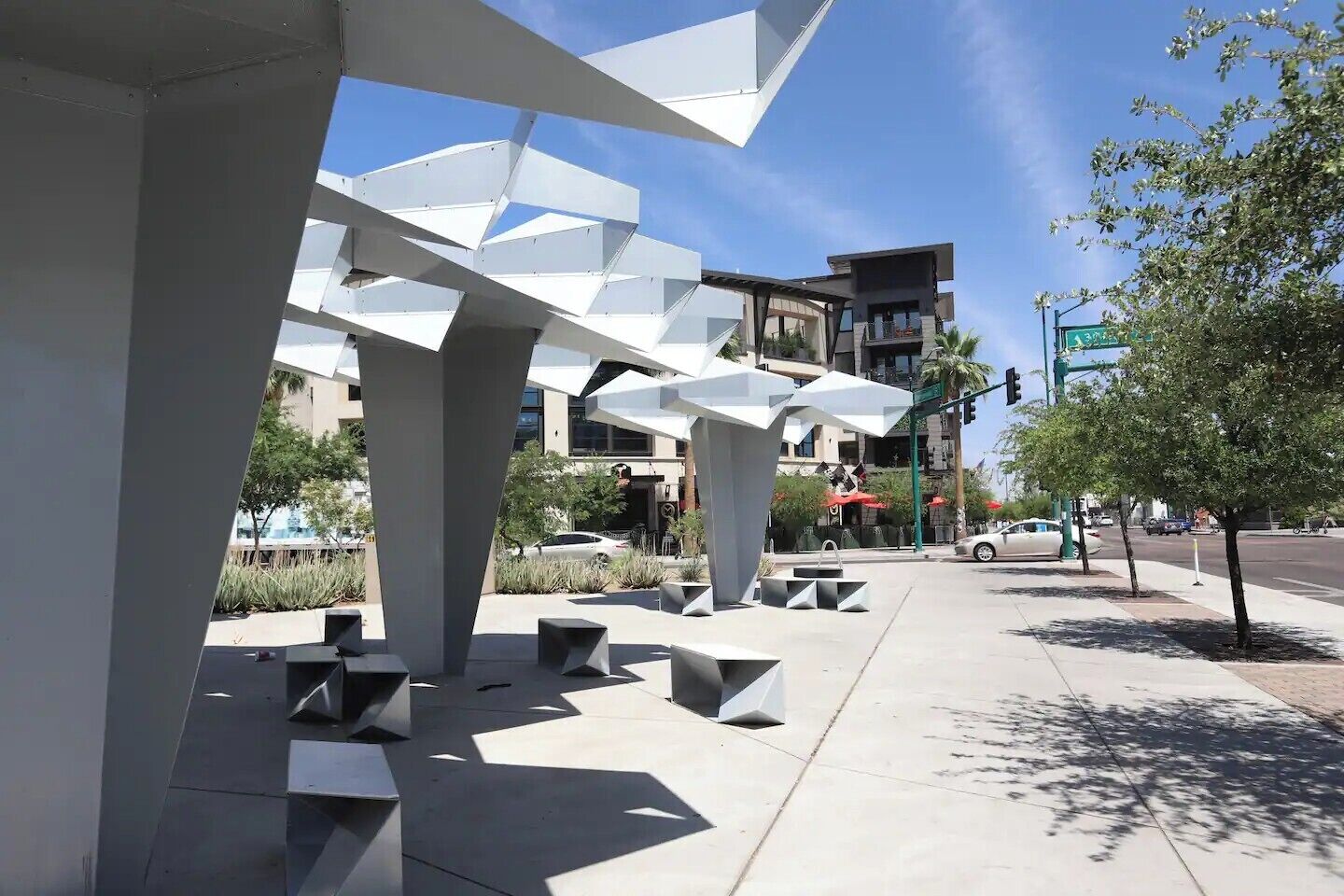 A modern outdoor seating area with geometric structures and a clear sky.