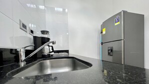 Una cocina con un lavamanos de acero inoxidable, una cafetera y un refrigerador.