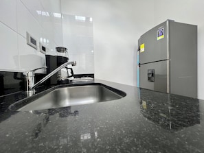 A kitchen with a stainless steel sink, a coffee maker, and a refrigerator. - Makondo House in Provenza by Nowa (Medellín)