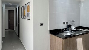 Una cocina moderna con baldosas blancas, encimera negra y una cafetera.